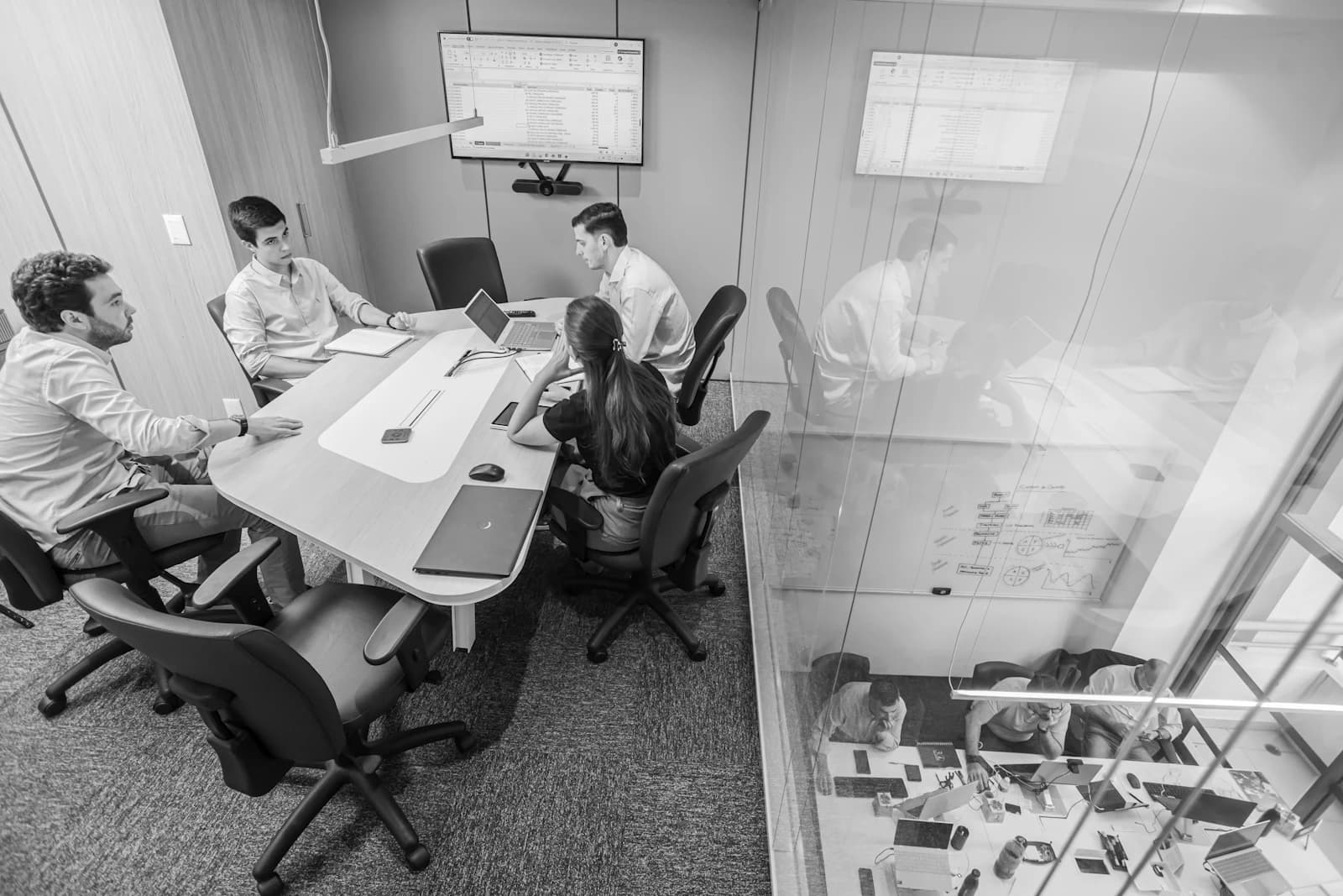A team discussing work around a table in a glass-walled conference room